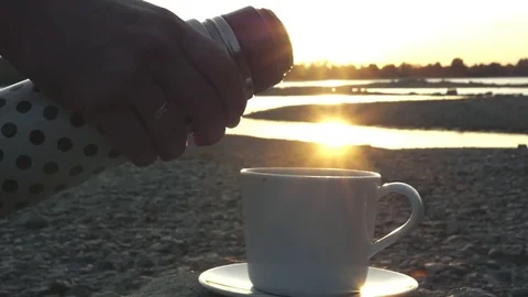 Pour a cup of invigorating fragrant drink from a thermos at sunset with Stock Footage 81179566