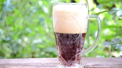 Pour dark beer on a background of green foliage Stock Footage 83732226