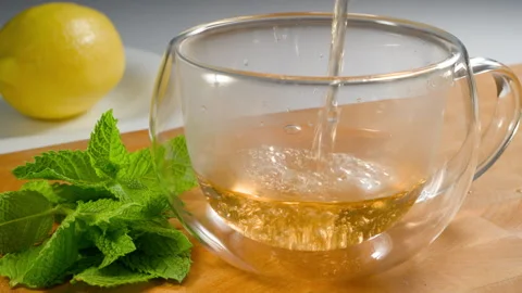 Pour green tea with mint into a cup. Stock Footage 310660869