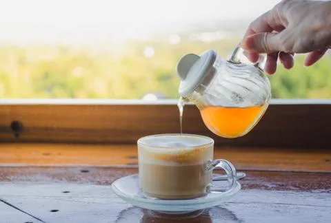 Pour the honey into the coffee cup.. Stock Photos