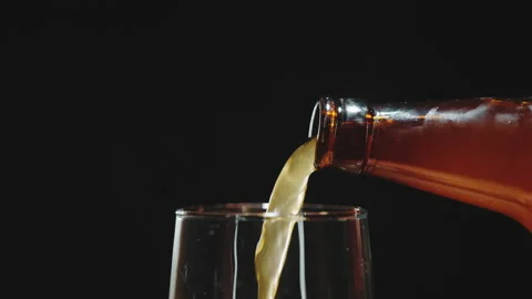 Pour light beer with bubbles into a glass on a black background. Stock Footage 171488509