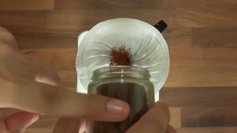 Pour medium roasted ground coffee into a glass coffee dripper with a paper filte Stock Footage 132017634