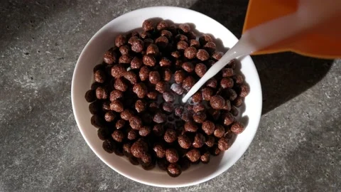 Pour milk into chocolate balls. Quick morning breakfast. Stock Footage 145660193