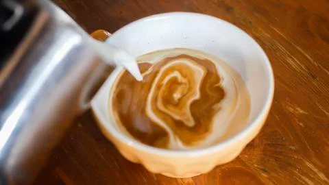Pour milk into coffee Stock Photos