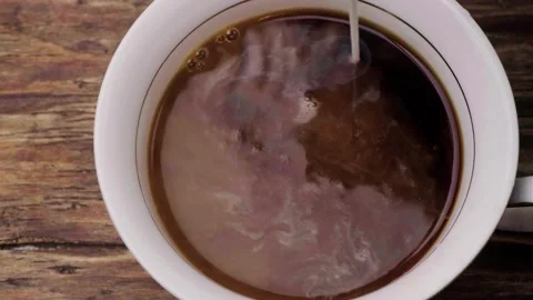 Pour milk into a cup of coffee Stock Footage 245628234