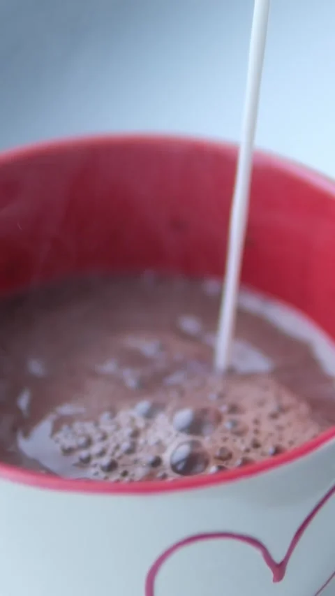 Pour milk into a cup of hot cocoa Stock Footage 302075221