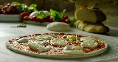 Pour the oil onto the raw pizza before baking it 4k Stock Footage 87400828