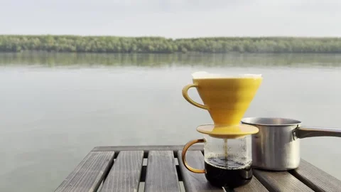 Pour Over Coffee Brewing by Calm Lake at Sunrise Video stock 334571792