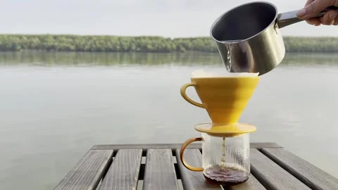 Pour Over Coffee Brewing by Calm Lake at Sunrise Video stock 334571850