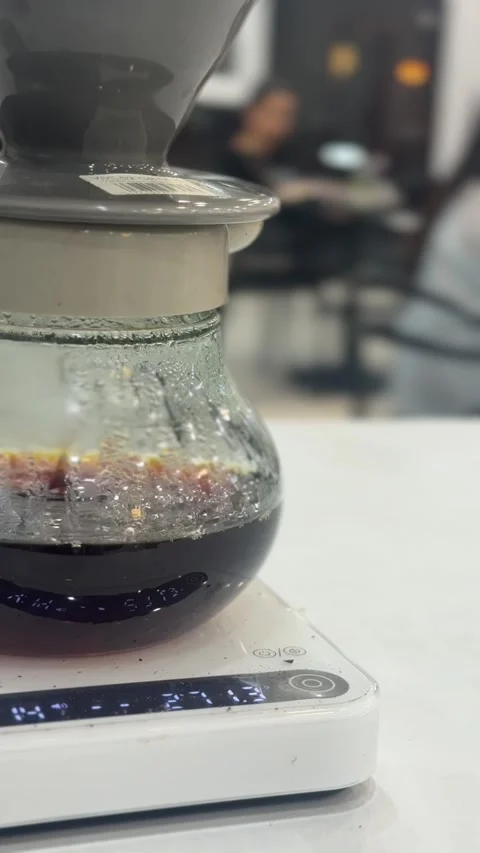 Pour-over coffee dripping into glass server on scale, vertical view Stock Footage 345160261