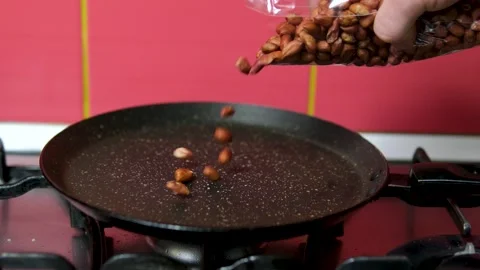 Pour peanuts into the pan Cooking crispy roasted salted peanuts. Nuts beans Stock Footage 305903058