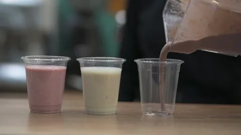 Pour into a plastic cup of chocolate milkshake in slow-motion Stock Footage 169042418