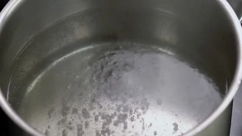 Pour salt into boiling water. Put raw chicken breast into boiling water. Stock Footage 170061312