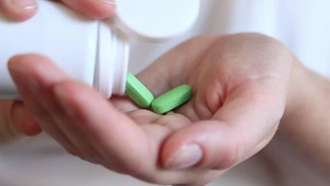Pour the tablets from the white bottle into your hand. Vitamins Stock Footage 247268365