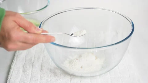 Pour a teaspoon of baking powder into a transparent bowl with eggs to prepare Stock Footage 231695714