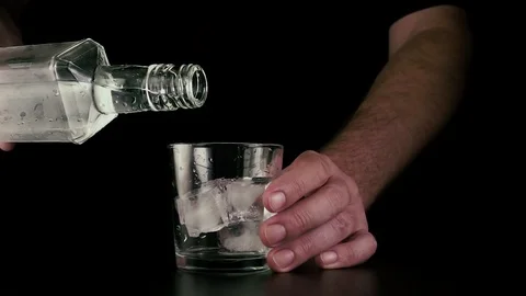 Pour vodka from a bottle into a glass with ice. Slow mo Stock Footage 76465178