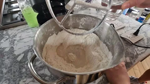 Pour water into a container with flour inside the mixer and mix Stock Footage 256245787