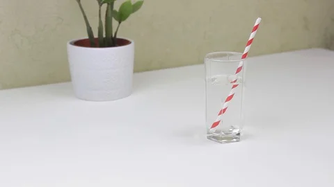 Pour water into a glass from a bottle and put a straw in a glass Stock Footage 127835341