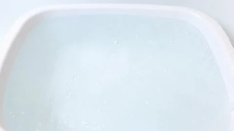 Pour water into a plastic container, basin. Pour running water into a container. Stock Footage 293689191