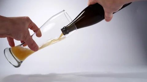 Pour Wheat Beer out of a Bottle in a Glass on white Background Stock Footage 126343748