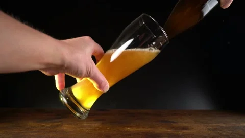 Pour Wheat Beer out of a Bottle in a Glass isolated on black Background Stock Footage 143869272