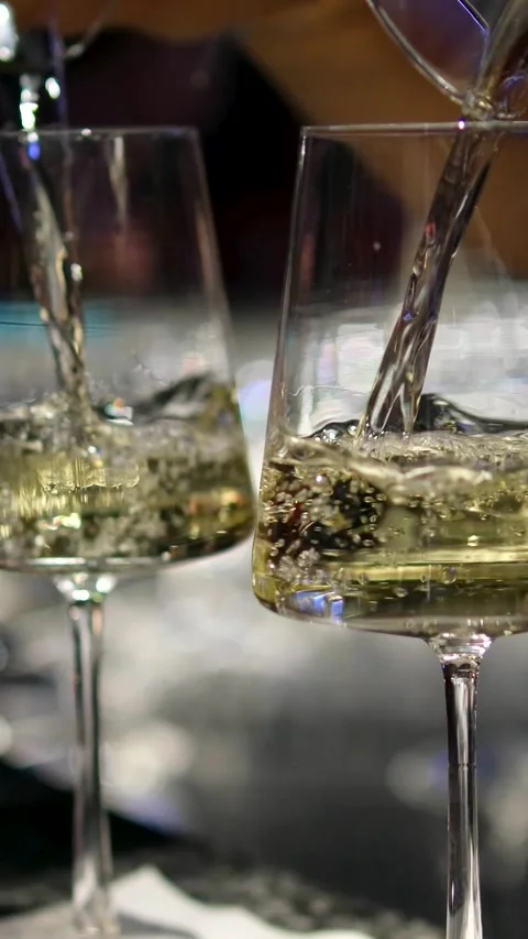 Pour white wine into glasses from both sides at the same time Beautiful View Of 動画素材 323920563