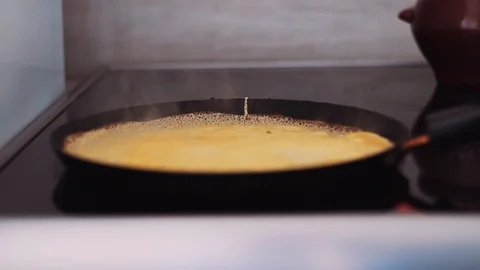 Poured pancake mix fried in a pan emitting puffs of steam Stock Footage 112017532