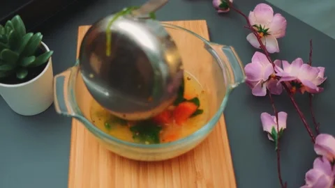 Pouring and stirring vegetable soup in glass bowl on dark table 스톡 동영상 342879121