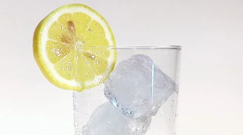 Pouring apple juice into glass of ice cubes with slice of lemon Stock Footage