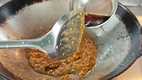 Pouring authentic fish sauce into a wok while making Pad Thai sauce. Stockbeeldmateriaal 339185829