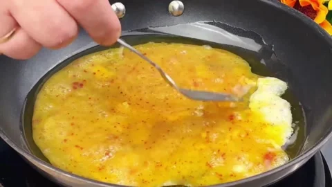 Pouring beaten egg mixture into a hot frying pan with oil to cook an omelette Stock Footage 324943344