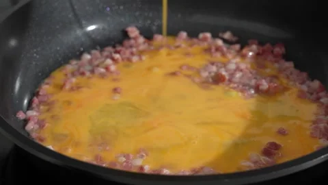 Pouring Beaten Eggs over Bacon in a Frying Pan Stock Footage 341483845