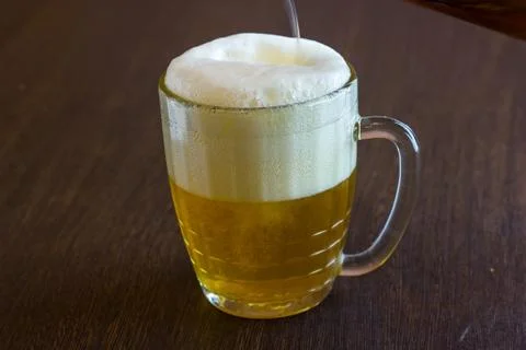 Pouring beer from bottle into mug at bar Stock Photos