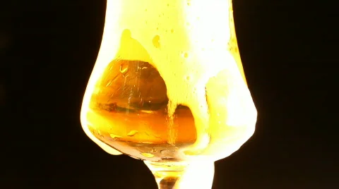 Pouring Beer with bubbles and foam in a glass isolated on black background Stock Footage 666872