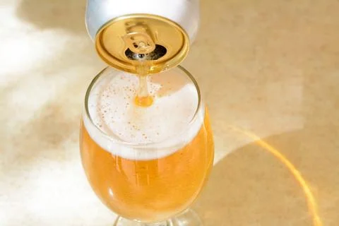 Pouring beer from can into glass on table, closeup. Space for text Stock Photos
