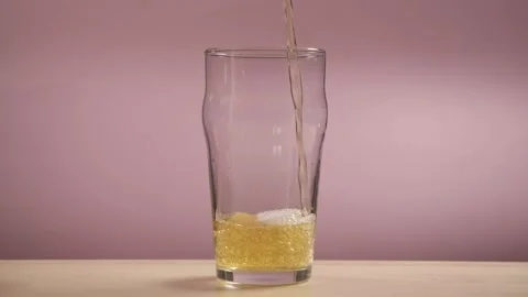 Pouring beer into the glass. beer on empty rosy background. Stockbeeldmateriaal 180995100