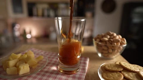 Pouring beer into the glass on a rotating table in the kitchen, slow motion Stock Footage 173214609