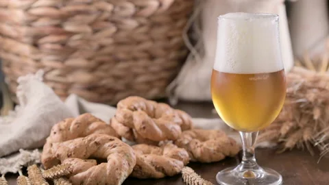 Pouring beer into the glass. Wheat spikelets with one mugs of beer on wooden Stockbeeldmateriaal 230098080