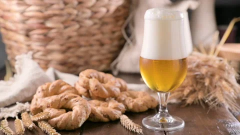 Pouring beer into the glass. Wheat spikelets with one mugs of beer on wooden Stock Footage 230098301