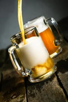 Pouring beer in glasses on rustic background Stock Photos