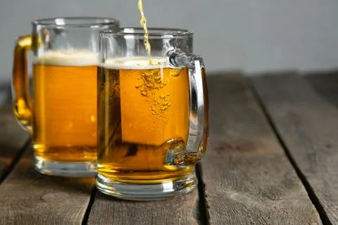 Pouring beer in glasses on rustic background Stock Photos