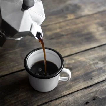 Pouring black coffee in the cup Stock Photos