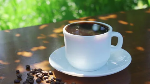 Pouring black coffee into a mug on a table in a garden landscape. Stock Footage 219079324