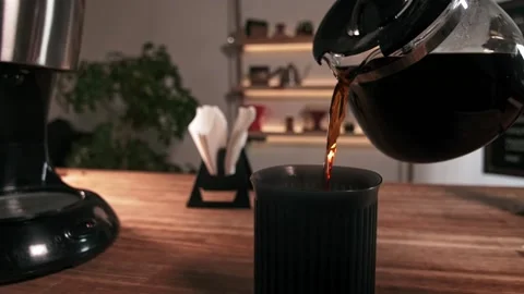 Pouring black filter coffee into a mug on wooden table Stockbeeldmateriaal 219721868
