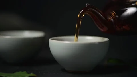 Pouring black leaf tea into a small ceramic cup, close-up. Stock Footage 144120835