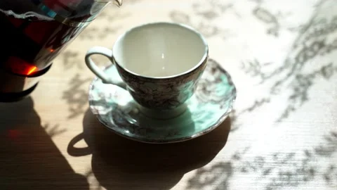 Pouring black tea into beautiful cup from French press. Steam comes from cup Stock Footage 134010865