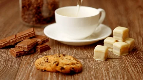 Pouring black tea in cup. Assortment of sweets, cookies and chocolate candies. Stock Footage 116822865