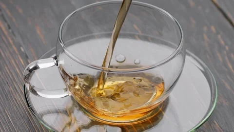 Pouring black tea into cup. Stream fresh aroma hot black tea into transparent Stock Footage 237615924