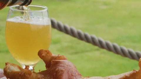 Pouring Blonde Beer with Fish and Chips Outdoors Stockbeeldmateriaal 315433332