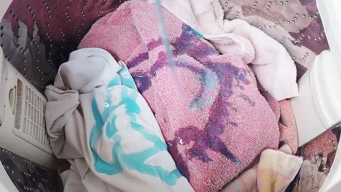 Pouring blue liquid laundry detergent into a washing machine with dirty clothes, Stock Footage 335643483